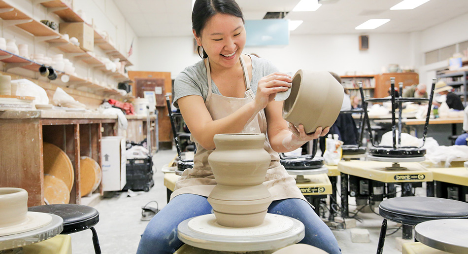 A young woman throws pottery in an art workshop