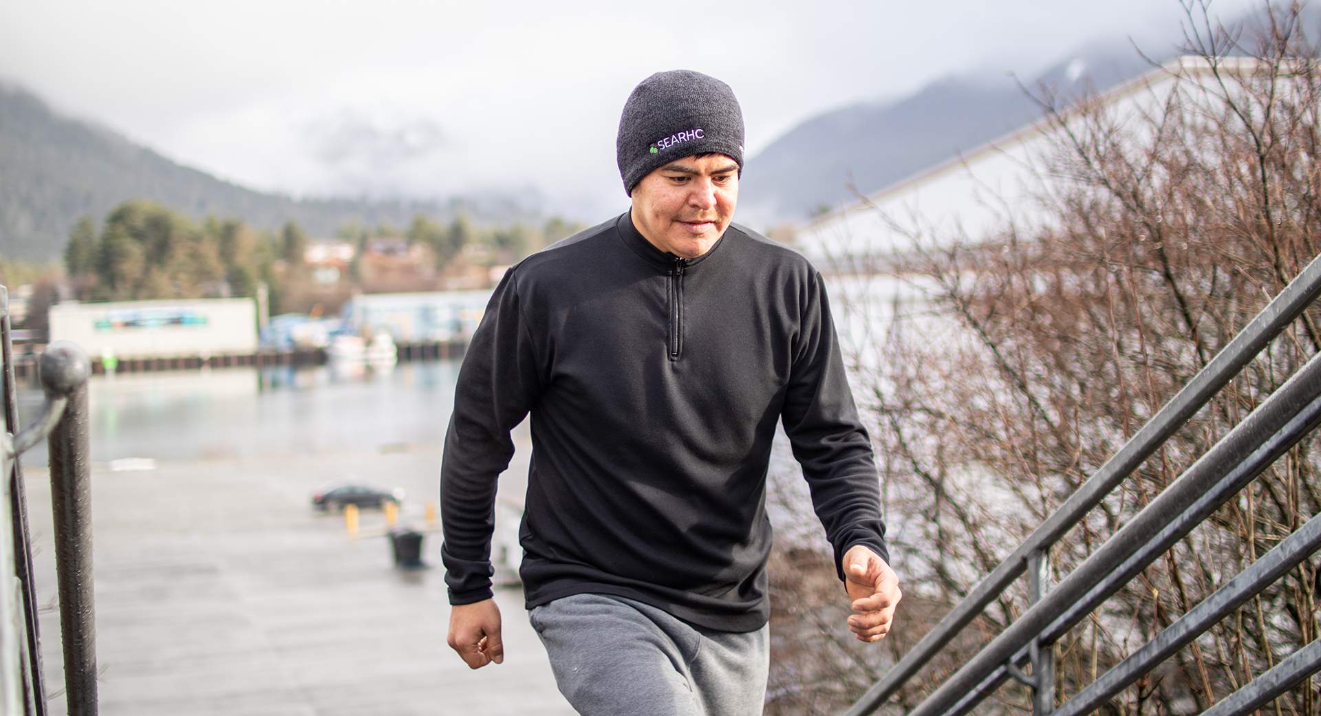 A man wearing a beanie walks briskly up the stairs for exercise