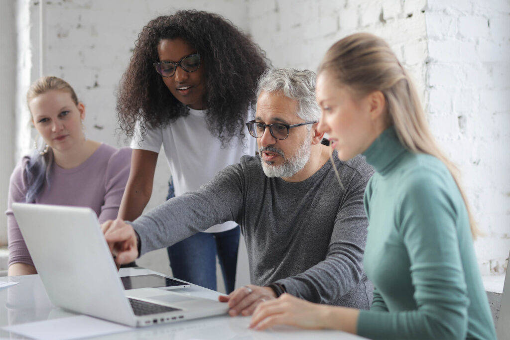 Coworkers discuss workforce marketing strategies around a laptop